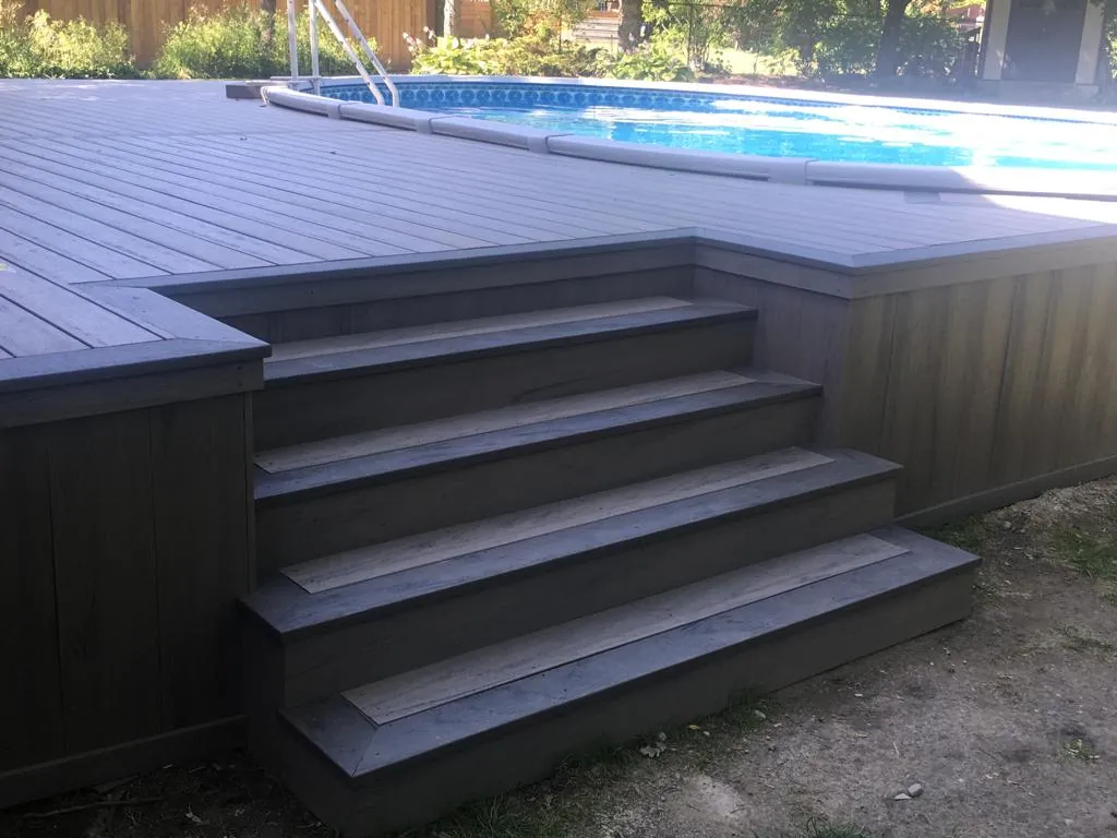 Dark grey composite deck stairs leading to an above-ground pool deck