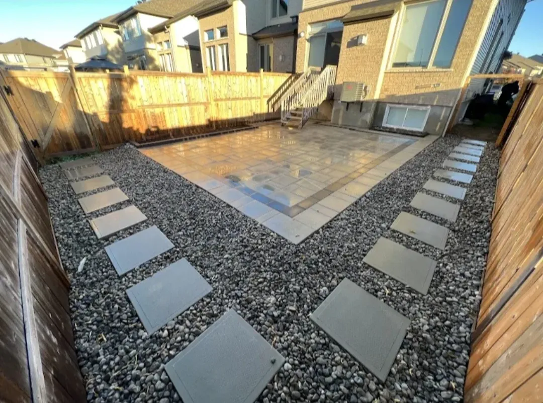 Backyard with square stepping stones set in decorative gravel and a paver patio